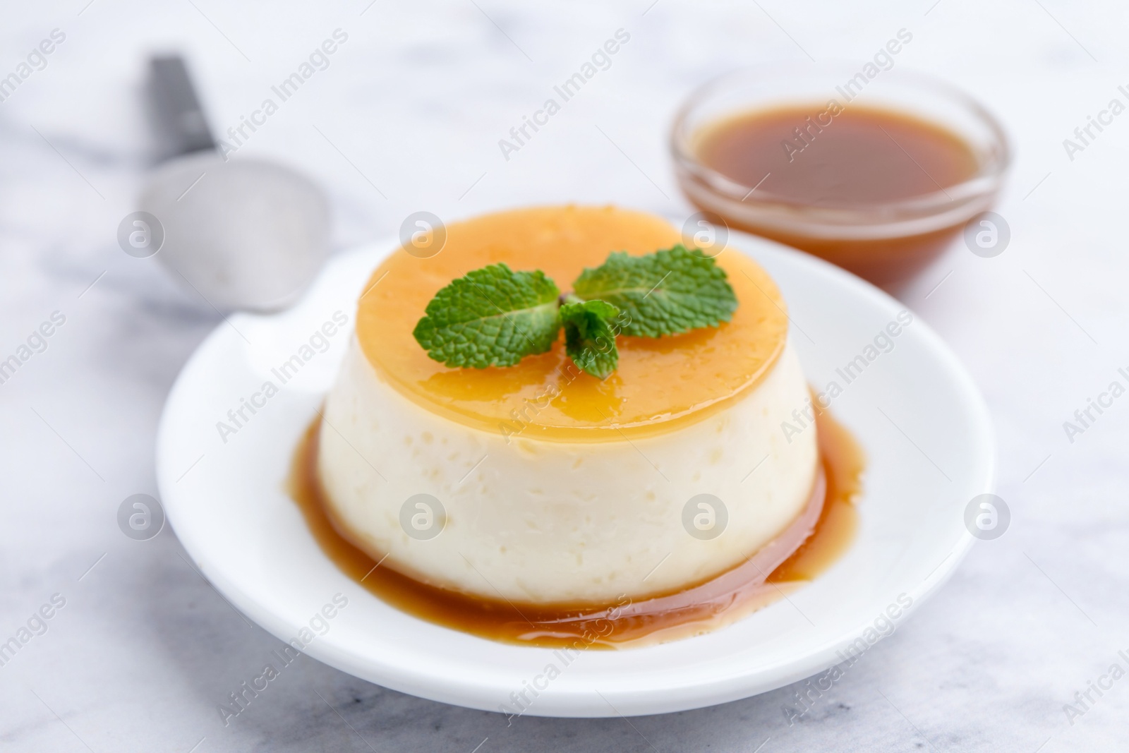 Photo of Tasty pudding with caramel sauce served on white marble table, closeup