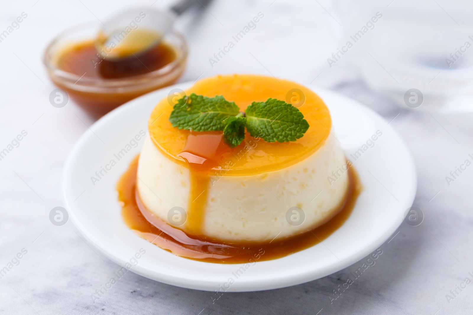 Photo of Tasty pudding with caramel sauce served on white marble table, closeup