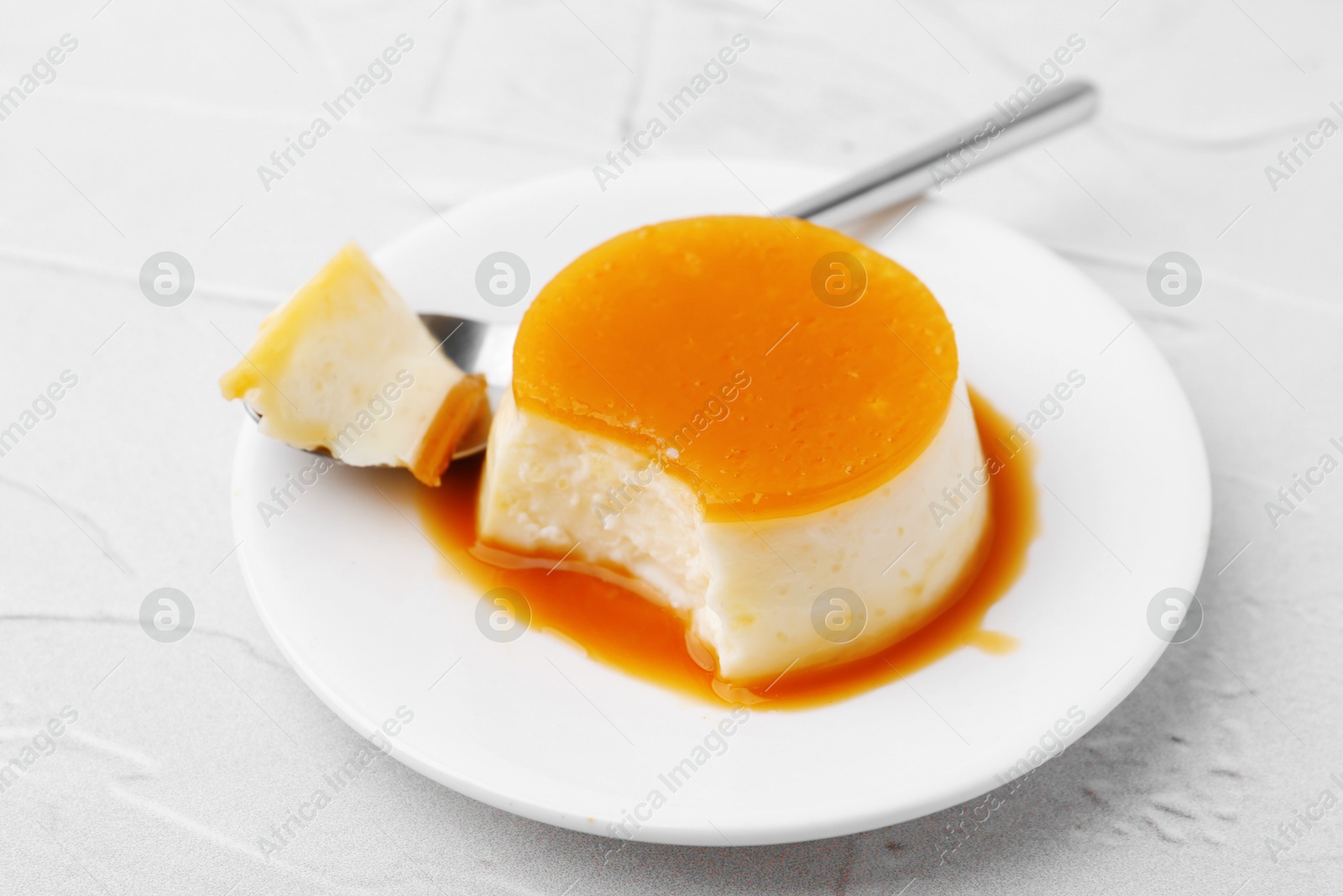 Photo of Tasty pudding with caramel sauce served on white textured table, closeup