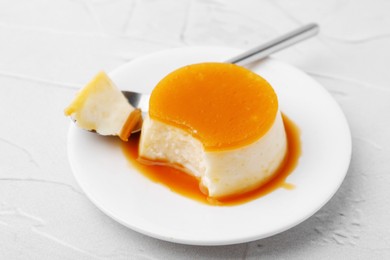 Photo of Tasty pudding with caramel sauce served on white textured table, closeup