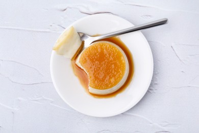 Photo of Tasty pudding with caramel sauce served on white textured table, top view