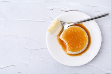 Photo of Tasty pudding with caramel sauce served on white textured table, top view. Space for text