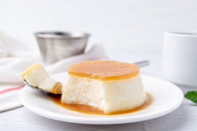 Photo of Tasty pudding with caramel sauce served on white textured table, closeup