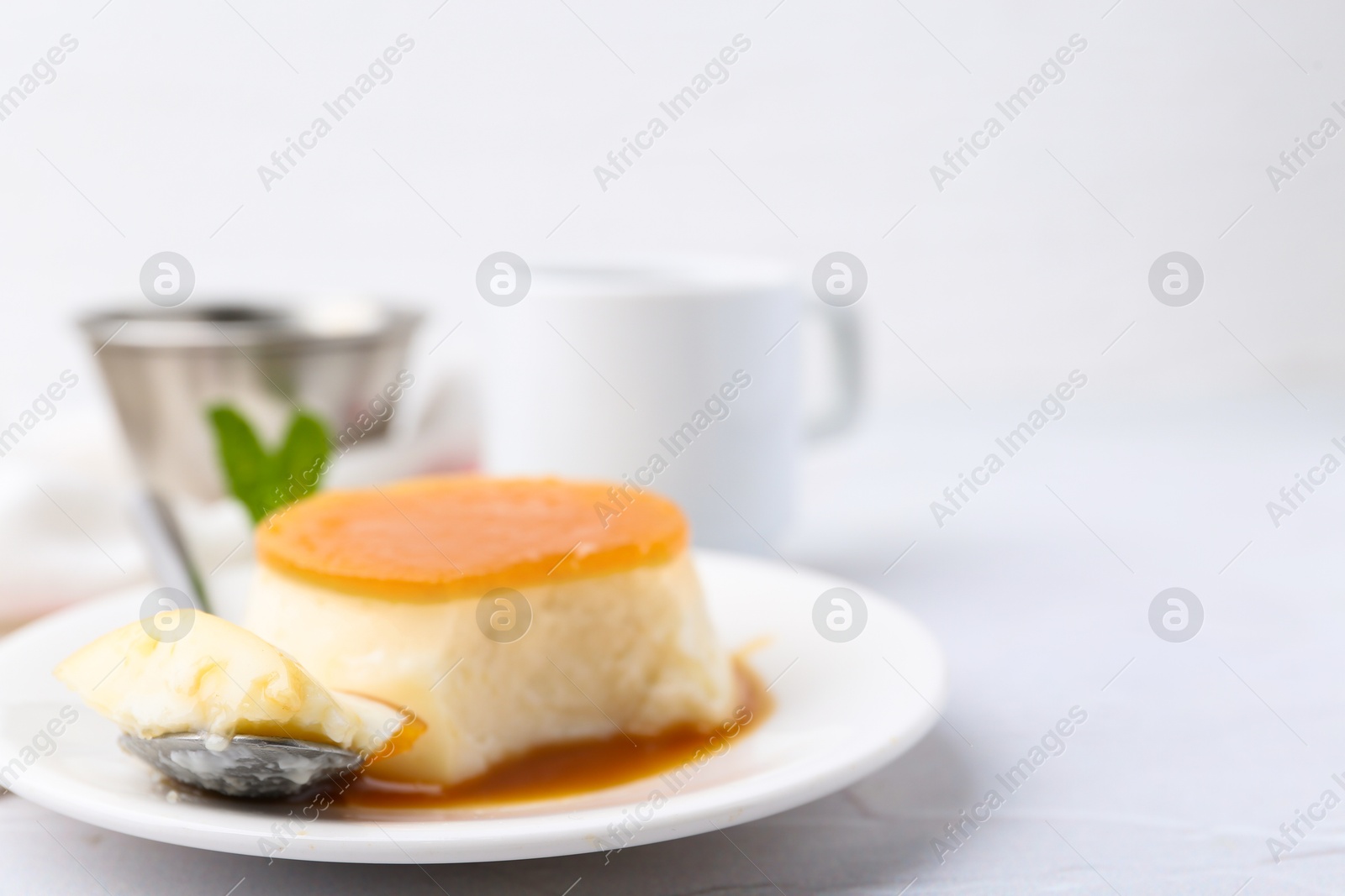 Photo of Tasty pudding with caramel sauce served on white textured table, closeup. Space for text