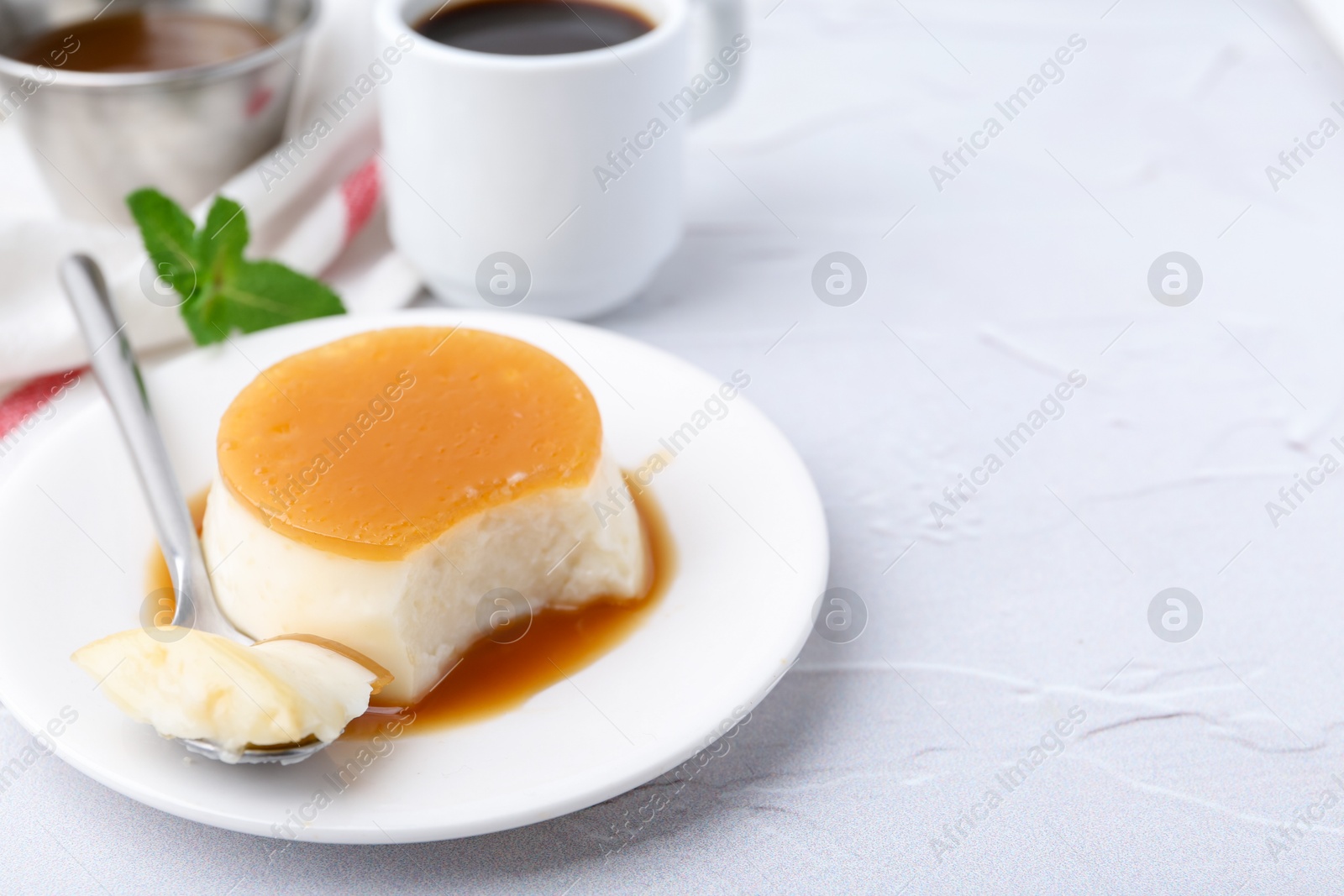 Photo of Tasty pudding with caramel sauce served on white textured table, closeup. Space for text