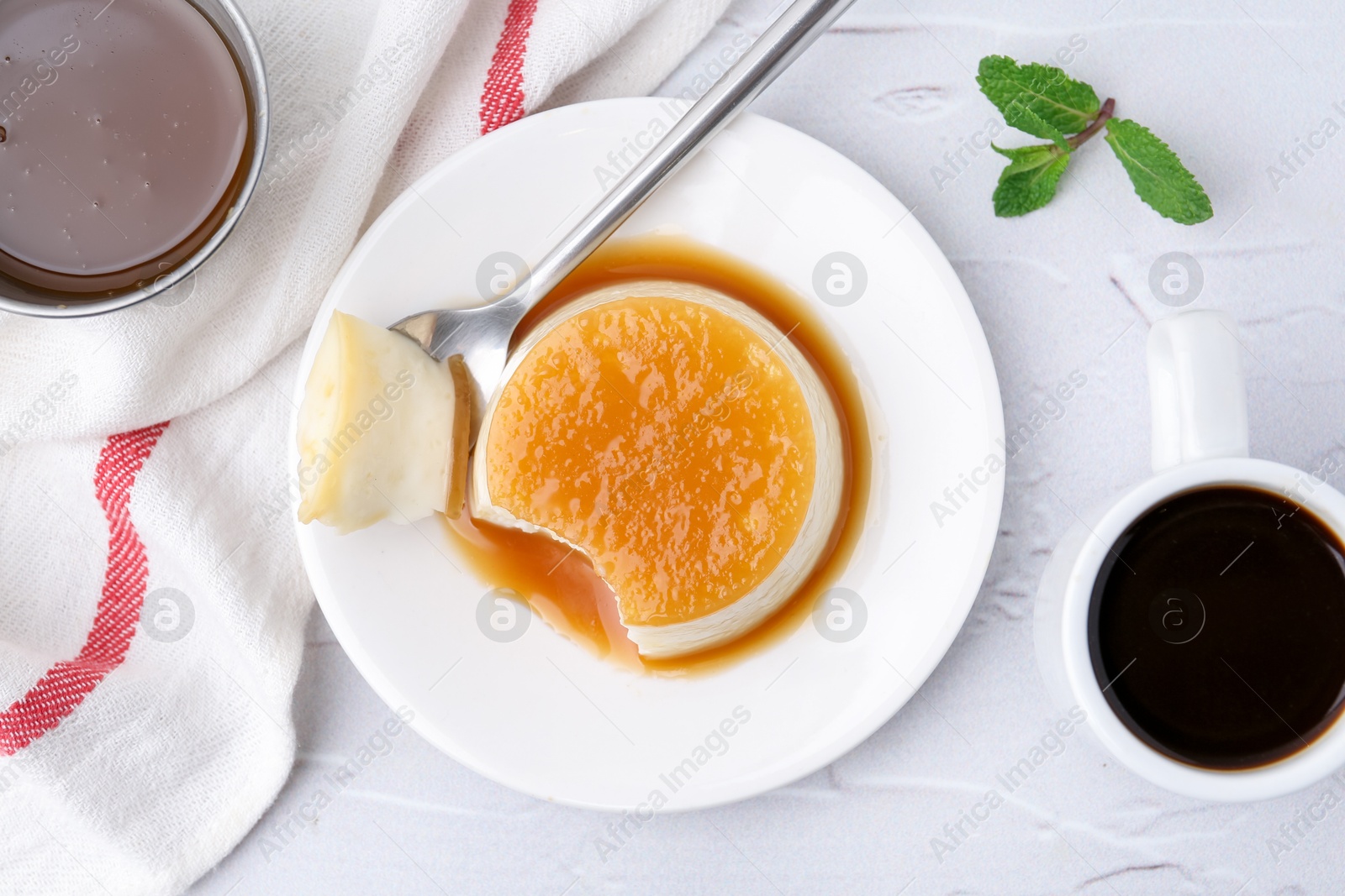 Photo of Tasty pudding with caramel sauce served on white textured table, flat lay