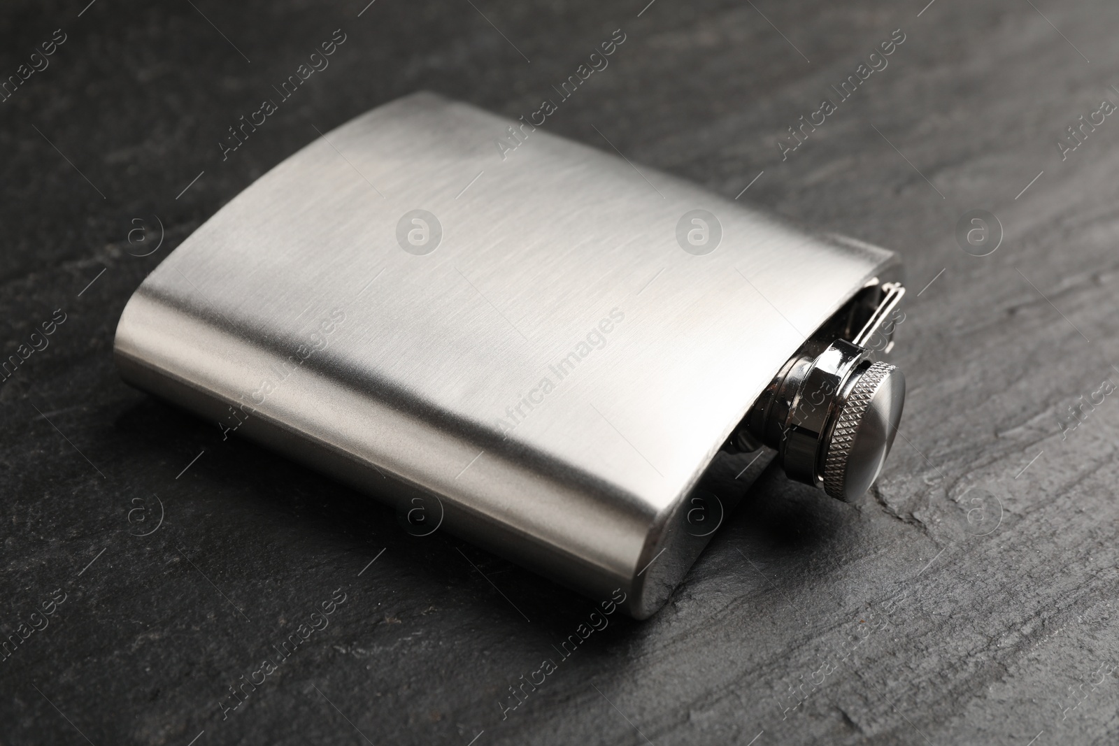 Photo of One hip flask on black table, closeup