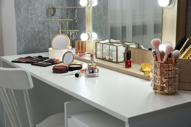 Photo of Makeup room. Different beauty products on white dressing table and mirror indoors