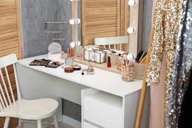 Photo of Makeup room. Mirror, dressing table, different beauty products and chair indoors