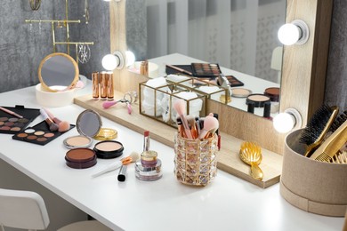 Photo of Makeup room. Different beauty products on white dressing table and mirror indoors