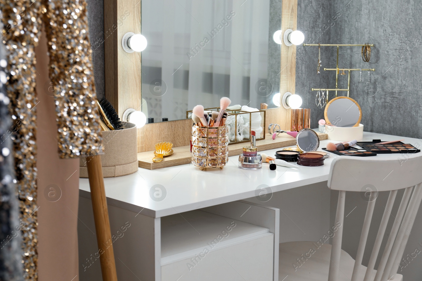 Photo of Makeup room. Mirror, dressing table, different beauty products and chair indoors