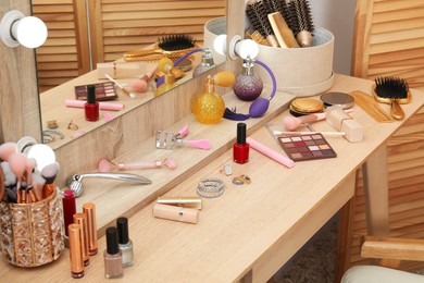 Photo of Makeup room. Different beauty products on wooden dressing table and mirror indoors