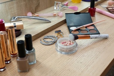 Photo of Makeup room. Different beauty products and jewelry on wooden dressing table, closeup