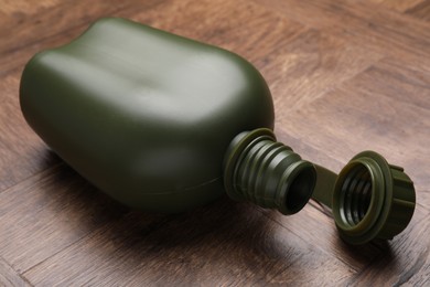 Photo of Green plastic canteen on wooden table, closeup