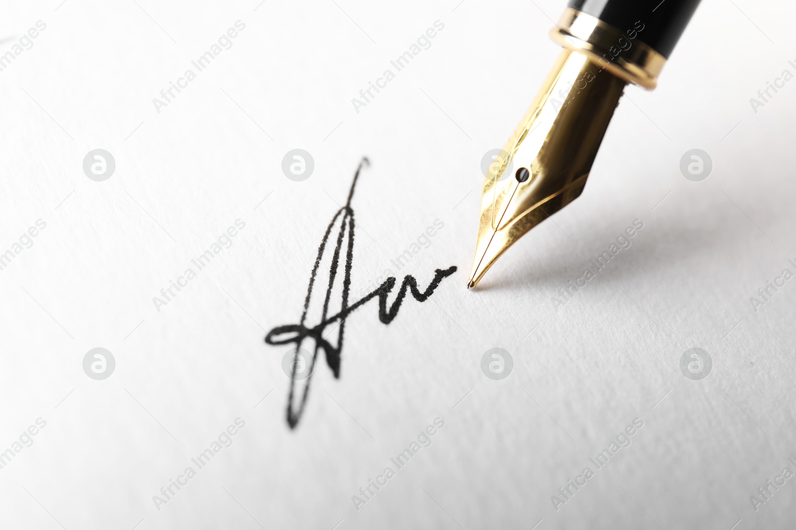 Photo of Fountain pen leaving signature on paper, closeup