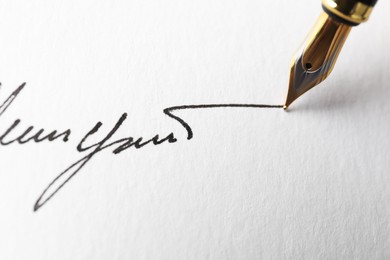 Photo of Fountain pen leaving signature on paper, closeup