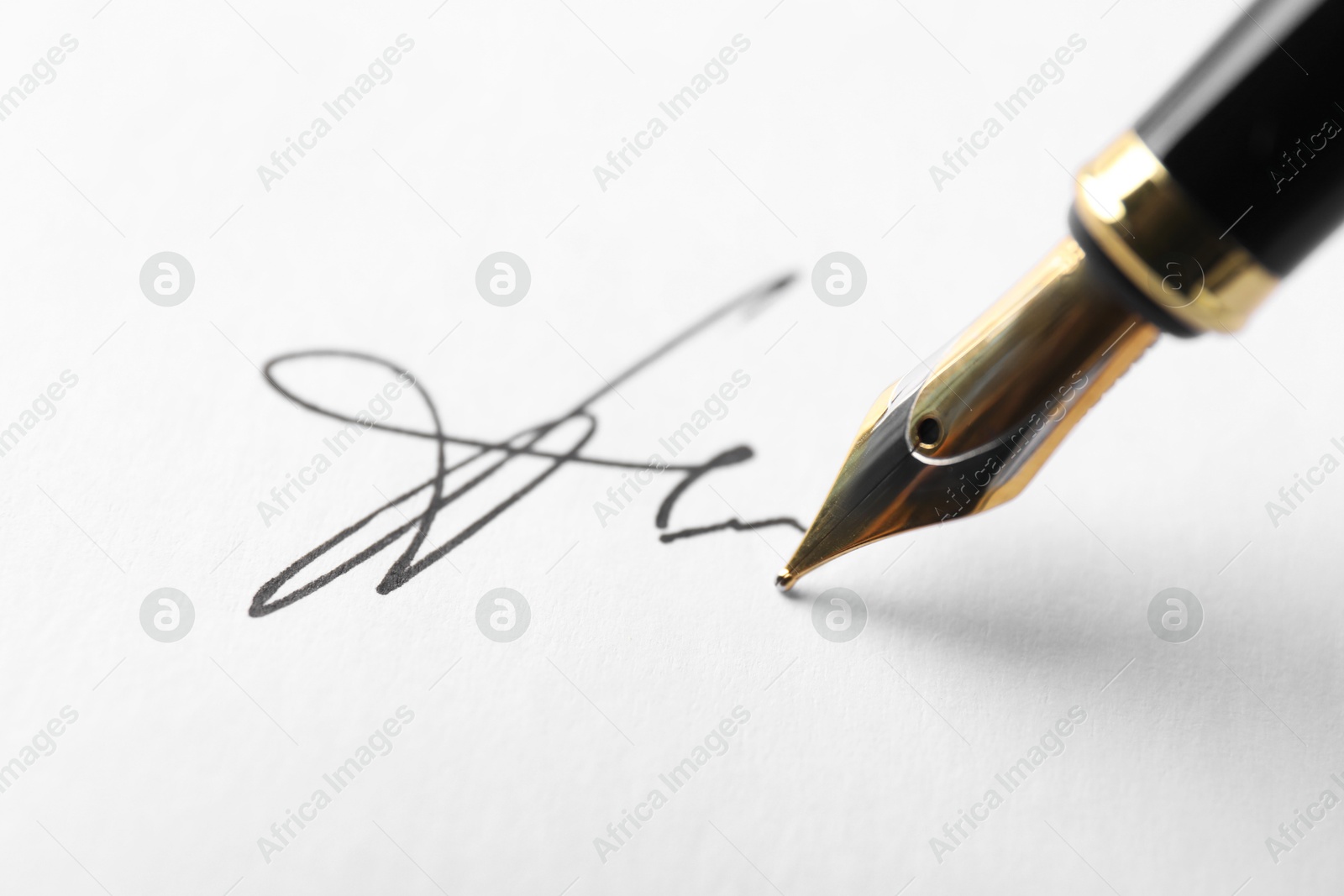 Photo of Fountain pen leaving signature on paper, closeup