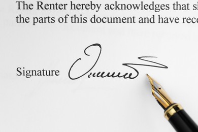 Photo of Fountain pen leaving signature on contract, top view