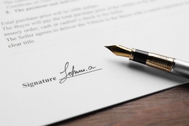 Photo of Fountain pen and signature on contract at wooden table, closeup