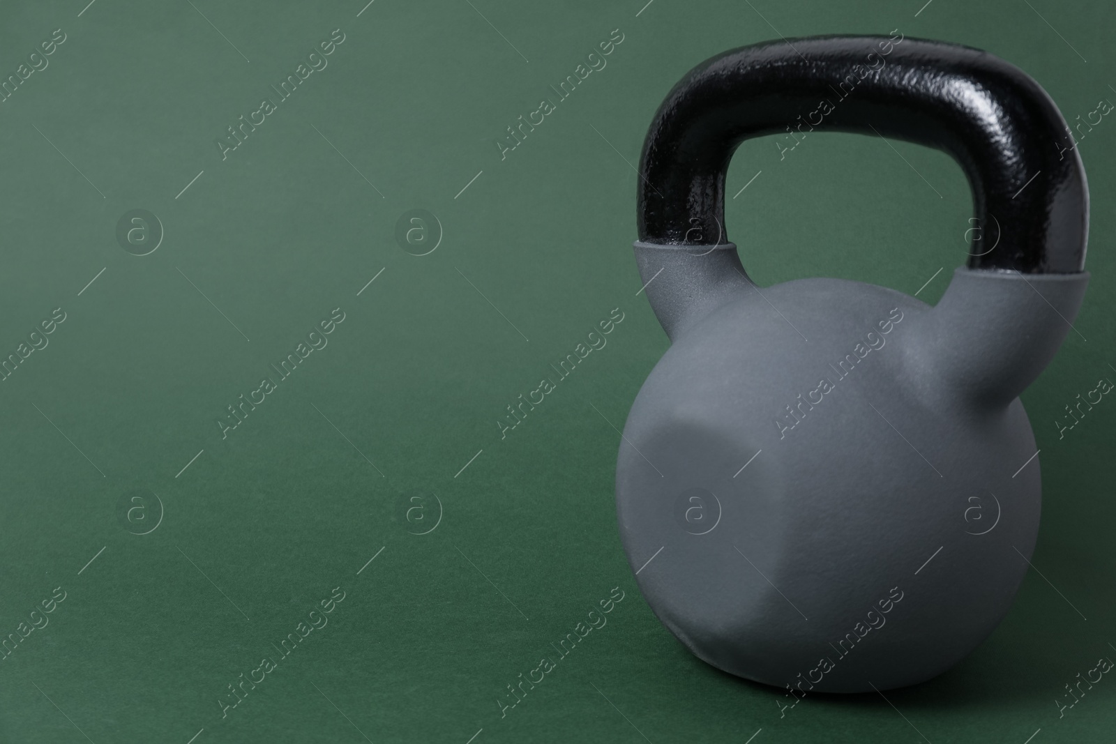 Photo of One kettlebell on dark green background. Space for text