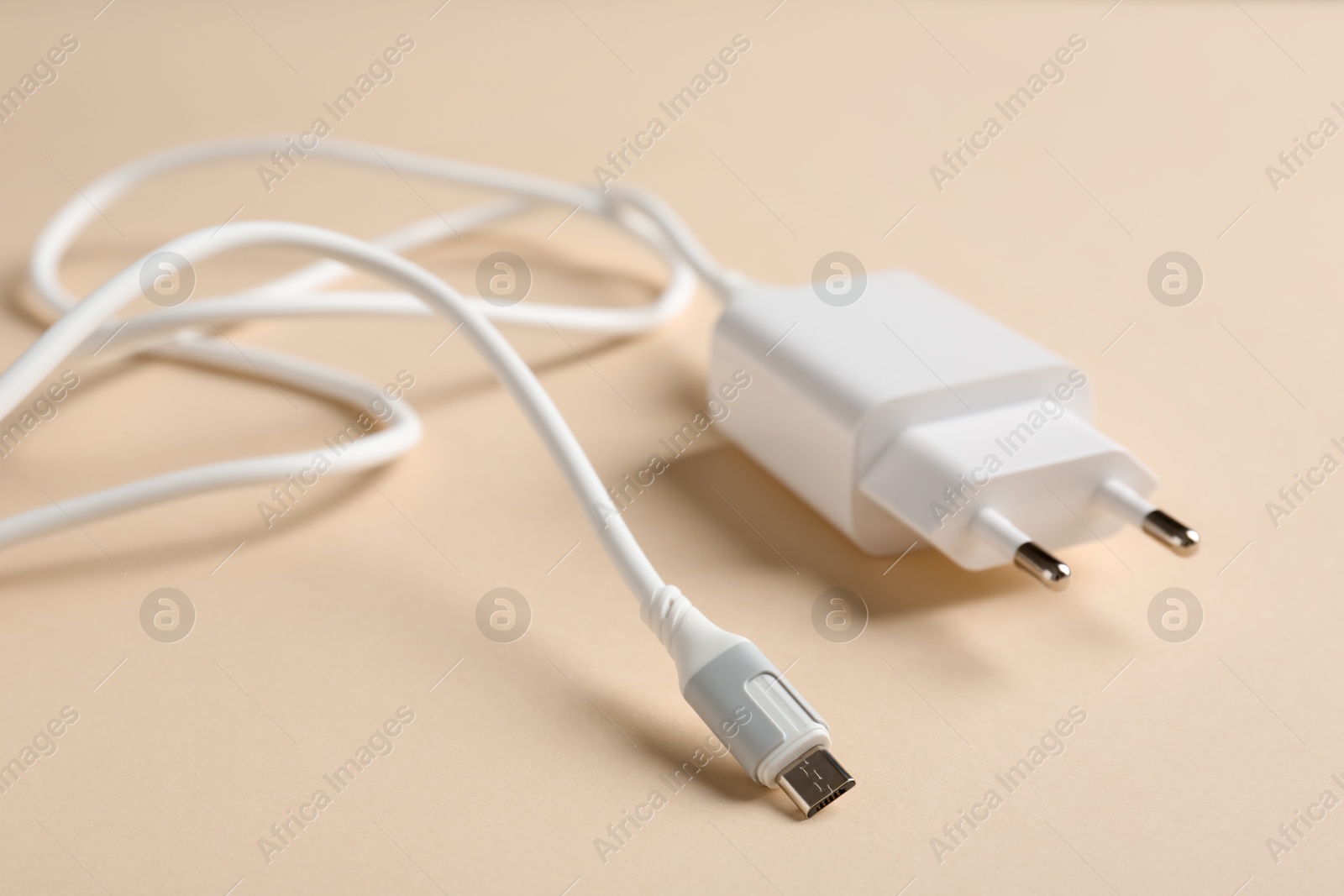 Photo of USB power adapter with charge cable on beige background, closeup