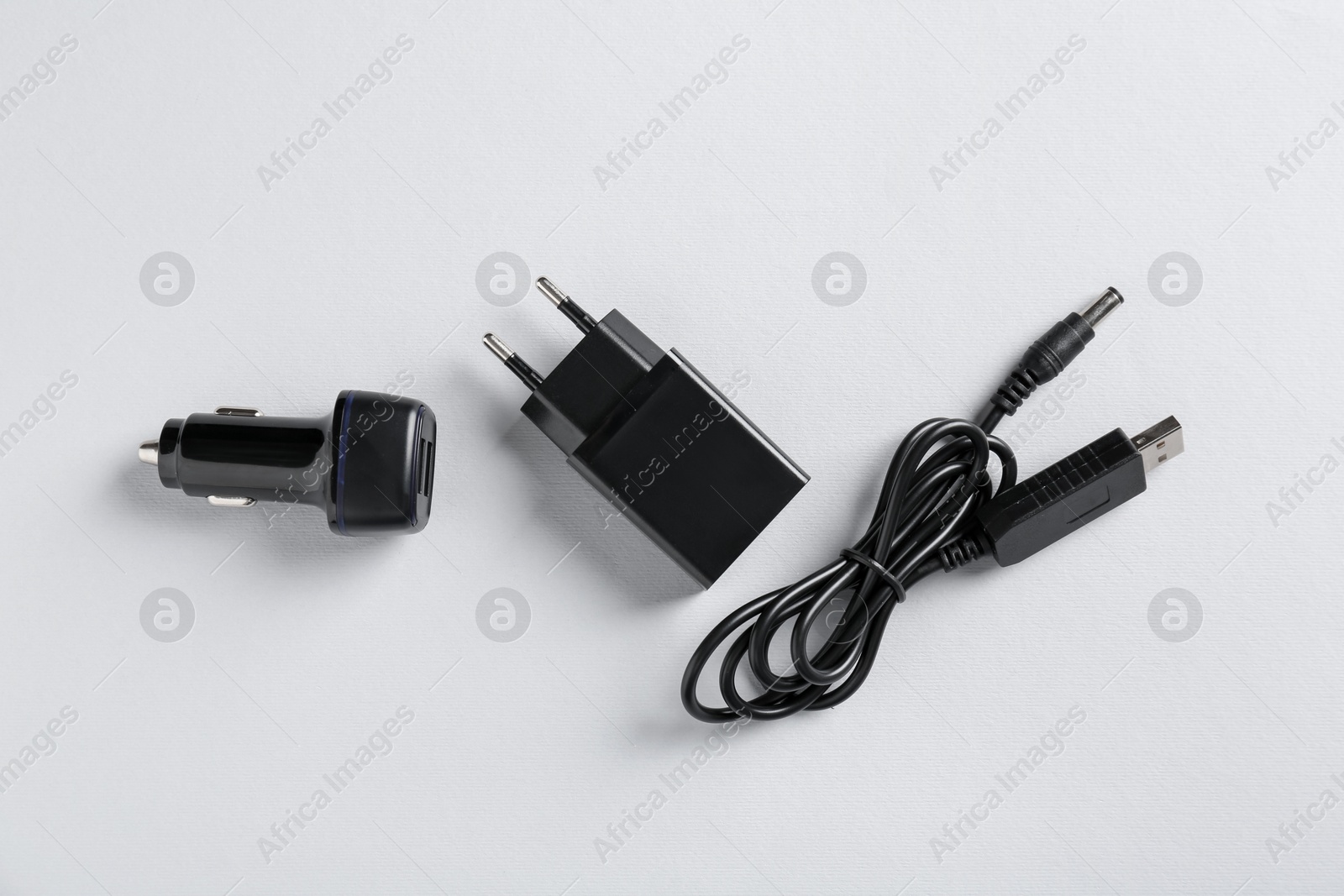 Photo of USB power adapter, charge cable and car charger on white background, flat lay