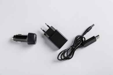 Photo of USB power adapter, charge cable and car charger on white background, flat lay