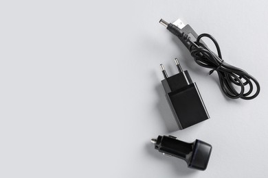 Photo of USB power adapter, charge cable and car charger on white background, flat lay. Space for text