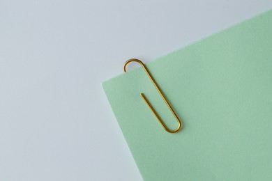 Paper note with clip on light background, top view. Space for text