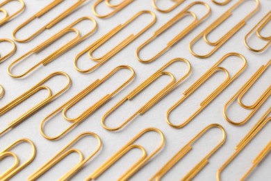 Photo of Golden paper clips on light background, closeup