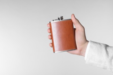 Photo of Man holding new hip flask on light grey background, closeup. Space for text