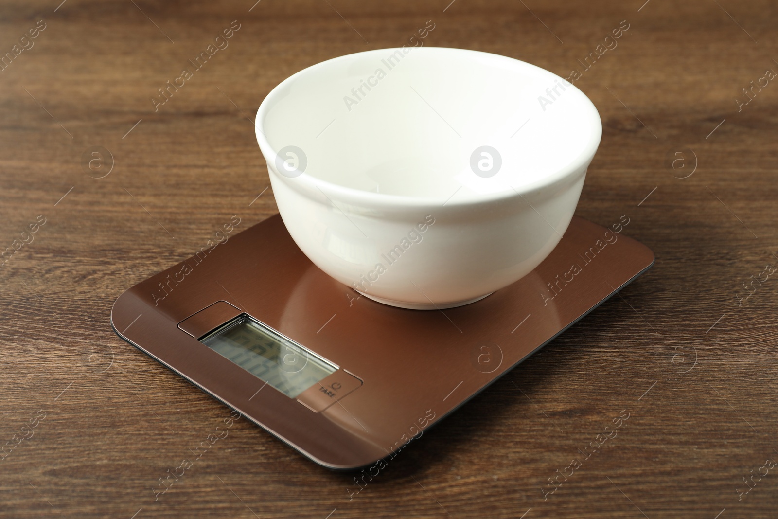 Photo of Modern electronic kitchen scale with bowl on wooden table, closeup