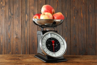 Photo of Retro mechanical kitchen scale with apples on wooden table