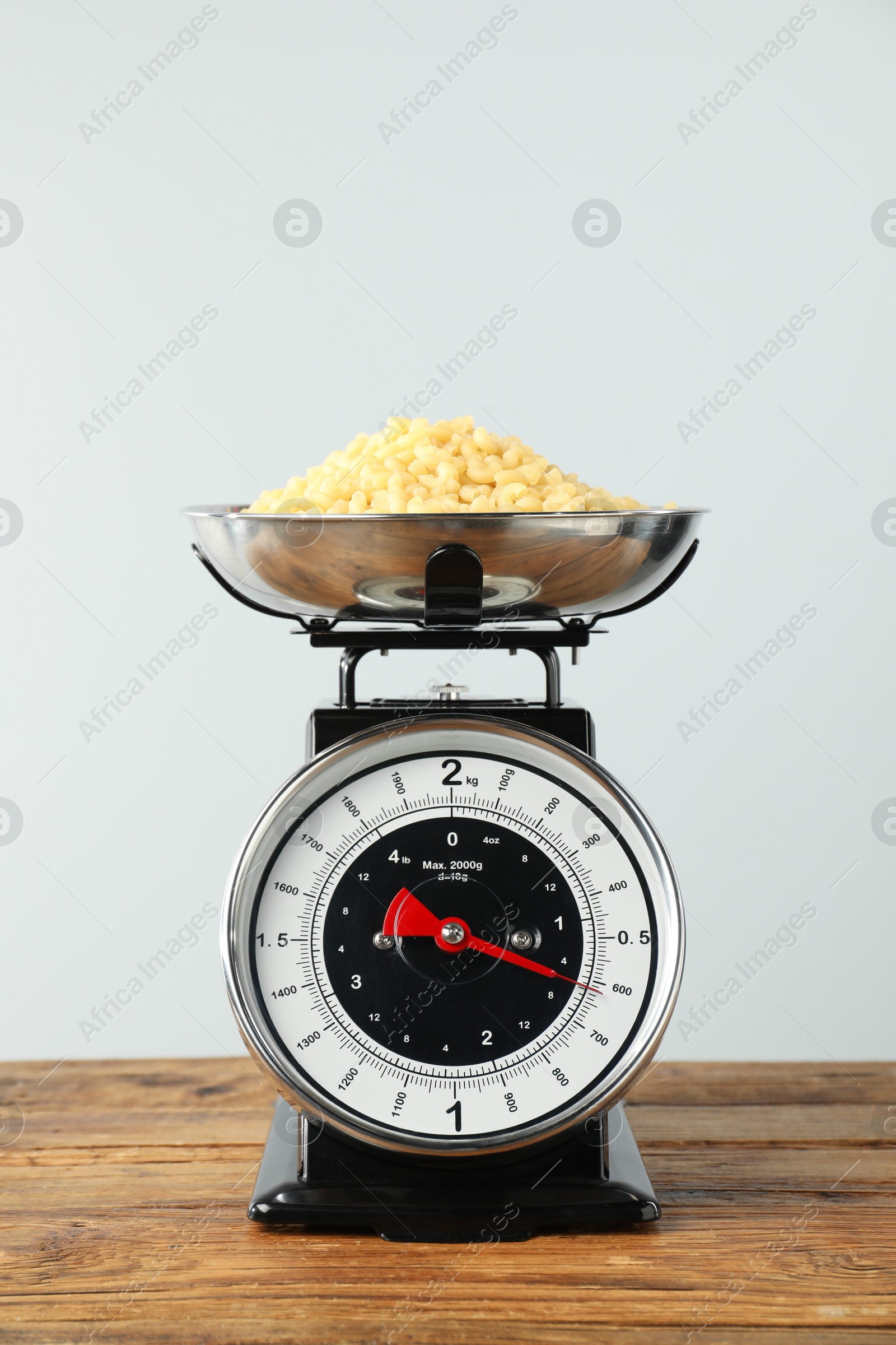 Photo of Retro mechanical kitchen scale with raw pasta on wooden table