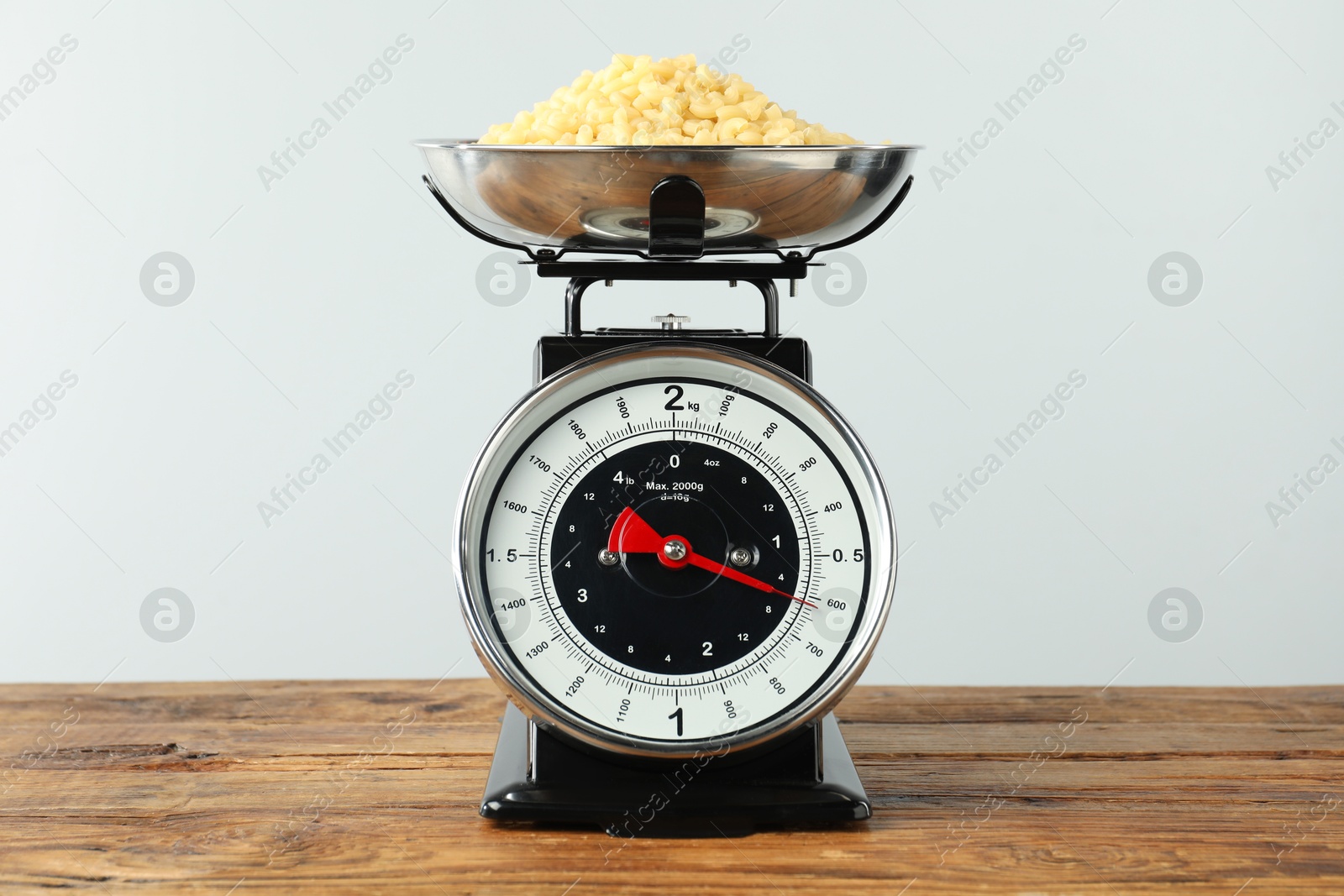 Photo of Retro mechanical kitchen scale with raw pasta on wooden table