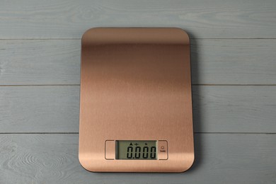 Photo of Modern electronic kitchen scale on grey wooden table, above view