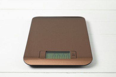 Photo of Modern electronic kitchen scale on white wooden table, closeup