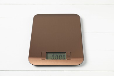 Photo of Modern electronic kitchen scale on white wooden table, closeup