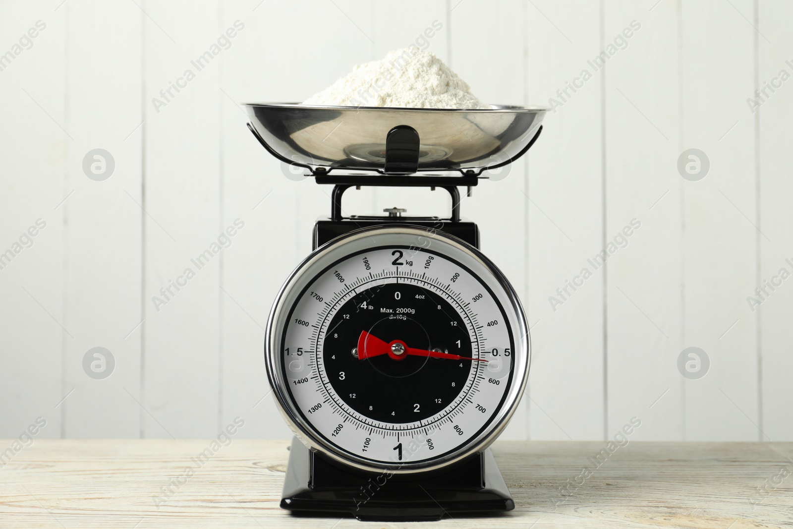 Photo of Retro mechanical kitchen scale with flour on wooden table