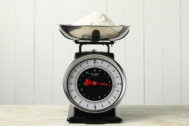 Photo of Retro mechanical kitchen scale with flour on wooden table