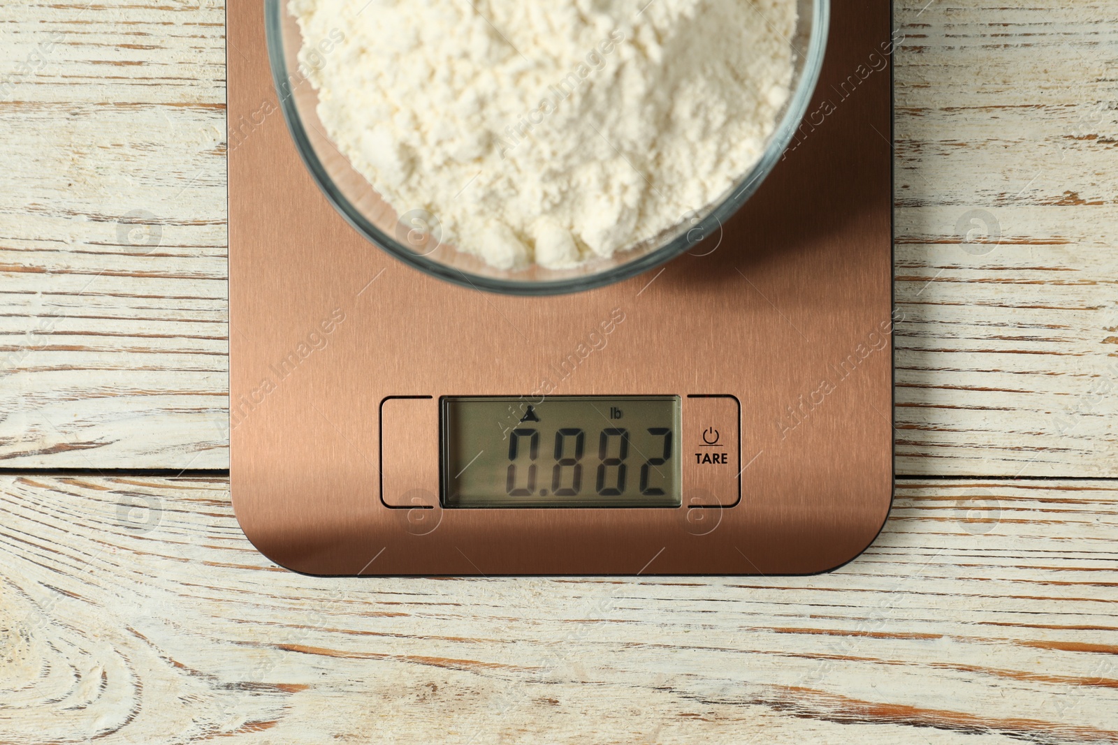 Photo of Modern electronic kitchen scale with bowl of flour on wooden table, top view