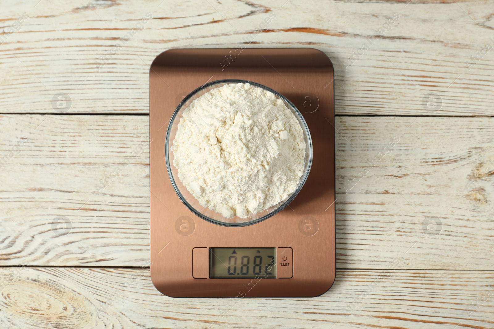 Photo of Modern electronic kitchen scale with bowl of flour on wooden table, top view