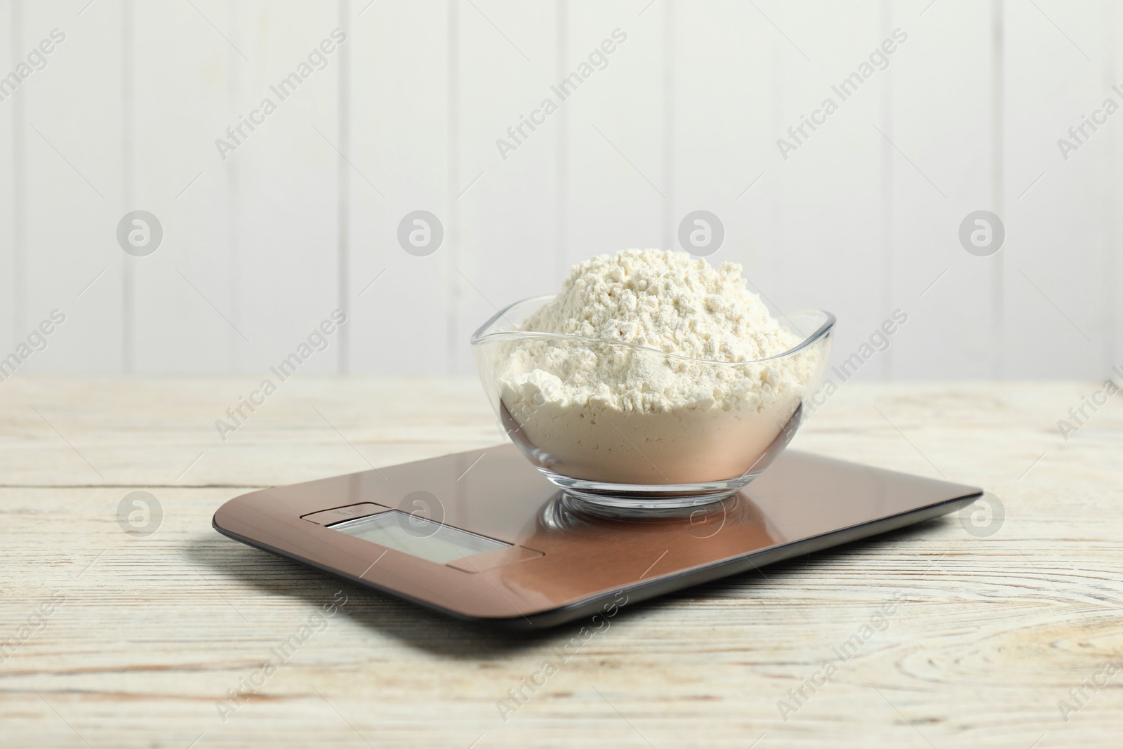 Photo of Modern electronic kitchen scale with bowl of flour on wooden table