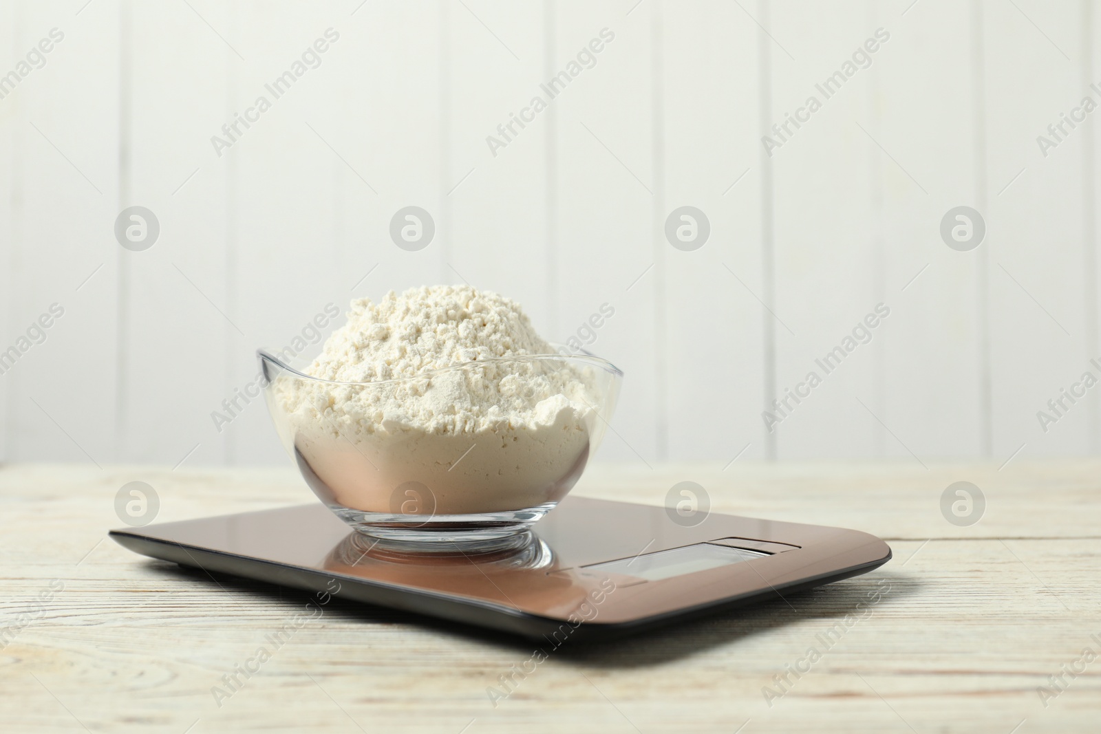 Photo of Modern electronic kitchen scale with bowl of flour on wooden table