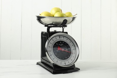 Photo of Retro mechanical kitchen scale with apples on white marble table