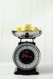 Photo of Retro mechanical kitchen scale with apples on white marble table