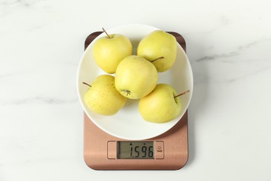 Photo of Modern electronic kitchen scale with apples on white marble table, top view