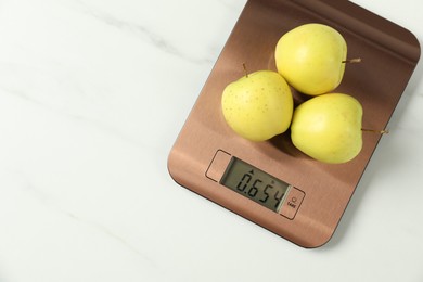 Photo of Modern electronic kitchen scale with apples on white marble table, top view. Space for text