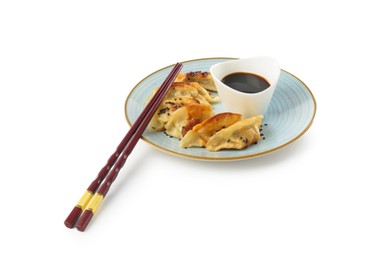 Photo of Tasty fried gyoza (dumplings), chopsticks and soy sauce isolated on white