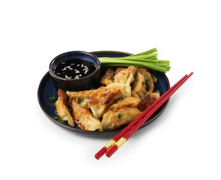 Photo of Tasty fried gyoza (dumplings), onion, chopsticks and soy sauce isolated on white